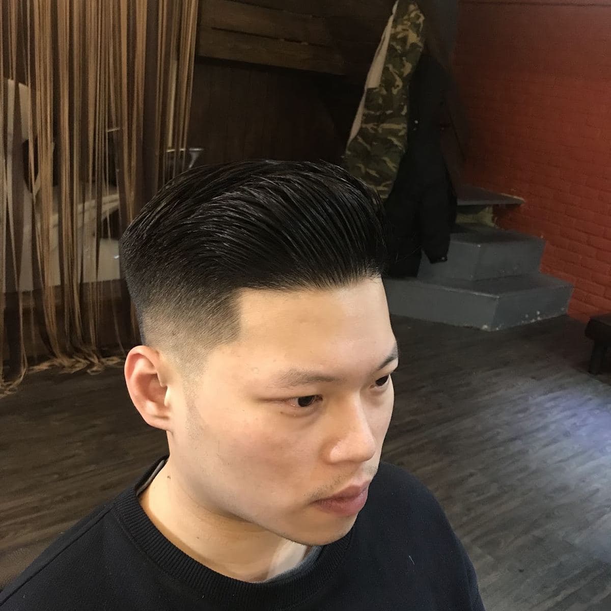 後梳油頭的斜側面，頂部頭髮帶光澤整片往後梳，側邊是乾淨的低漸層
