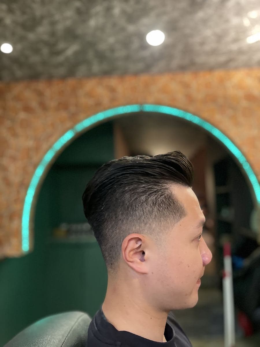側面看的後梳油頭,前額的頭髮吹出高度後往後帶,側邊推短成漸層